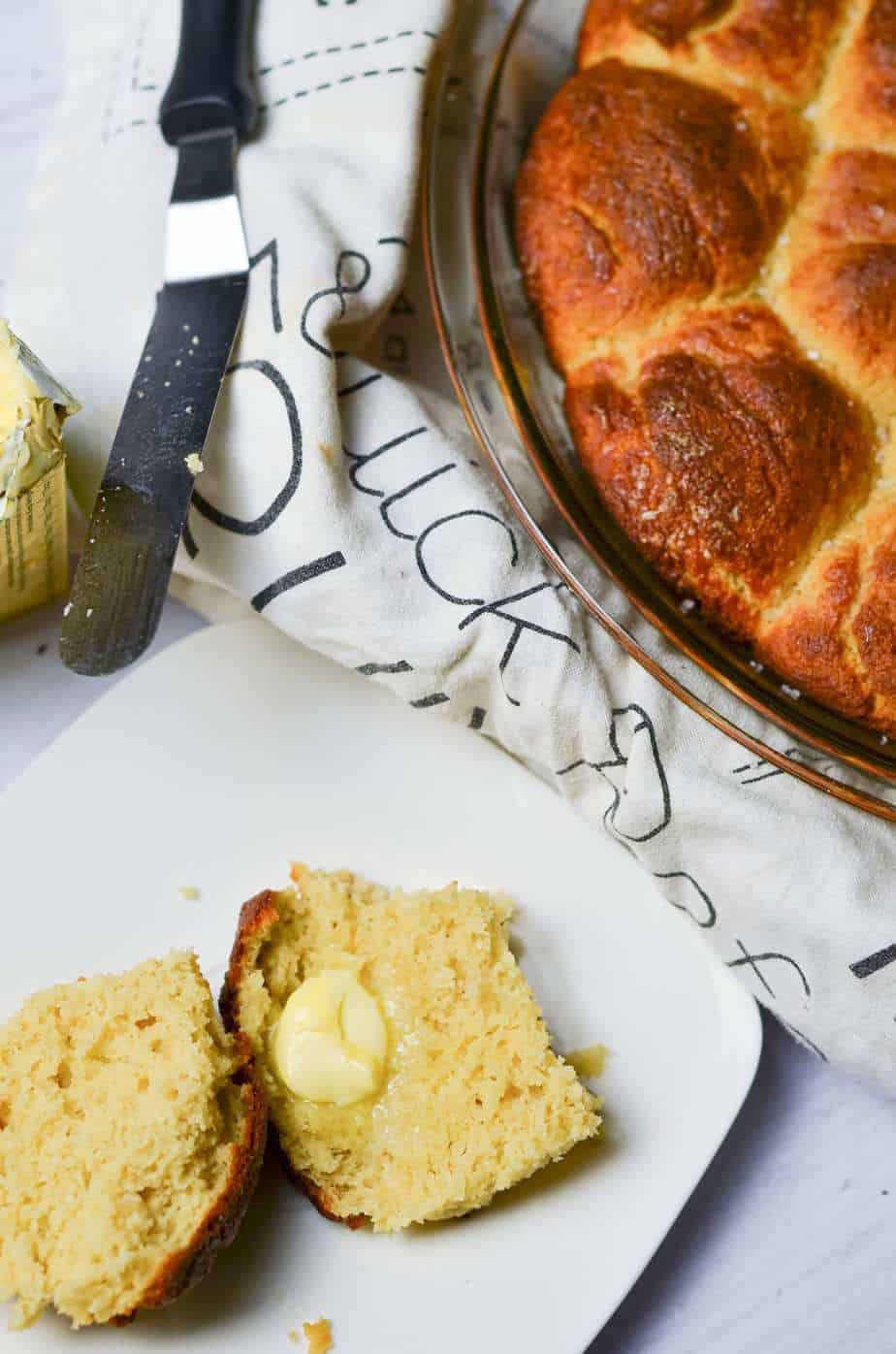 dinner rolls split open an din a pie dish with butter
