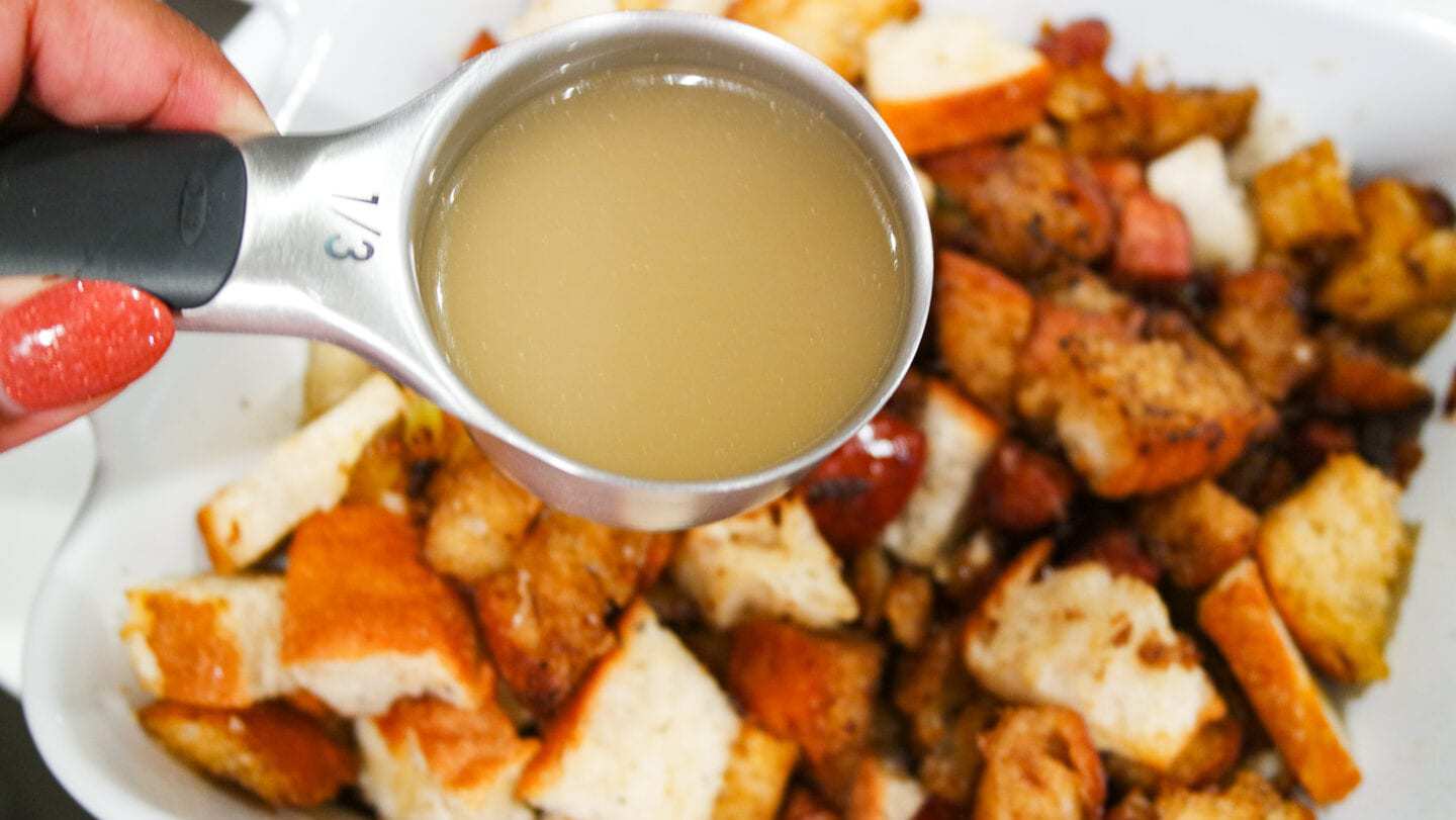 Pouring chicken broth into sausage stuffing.