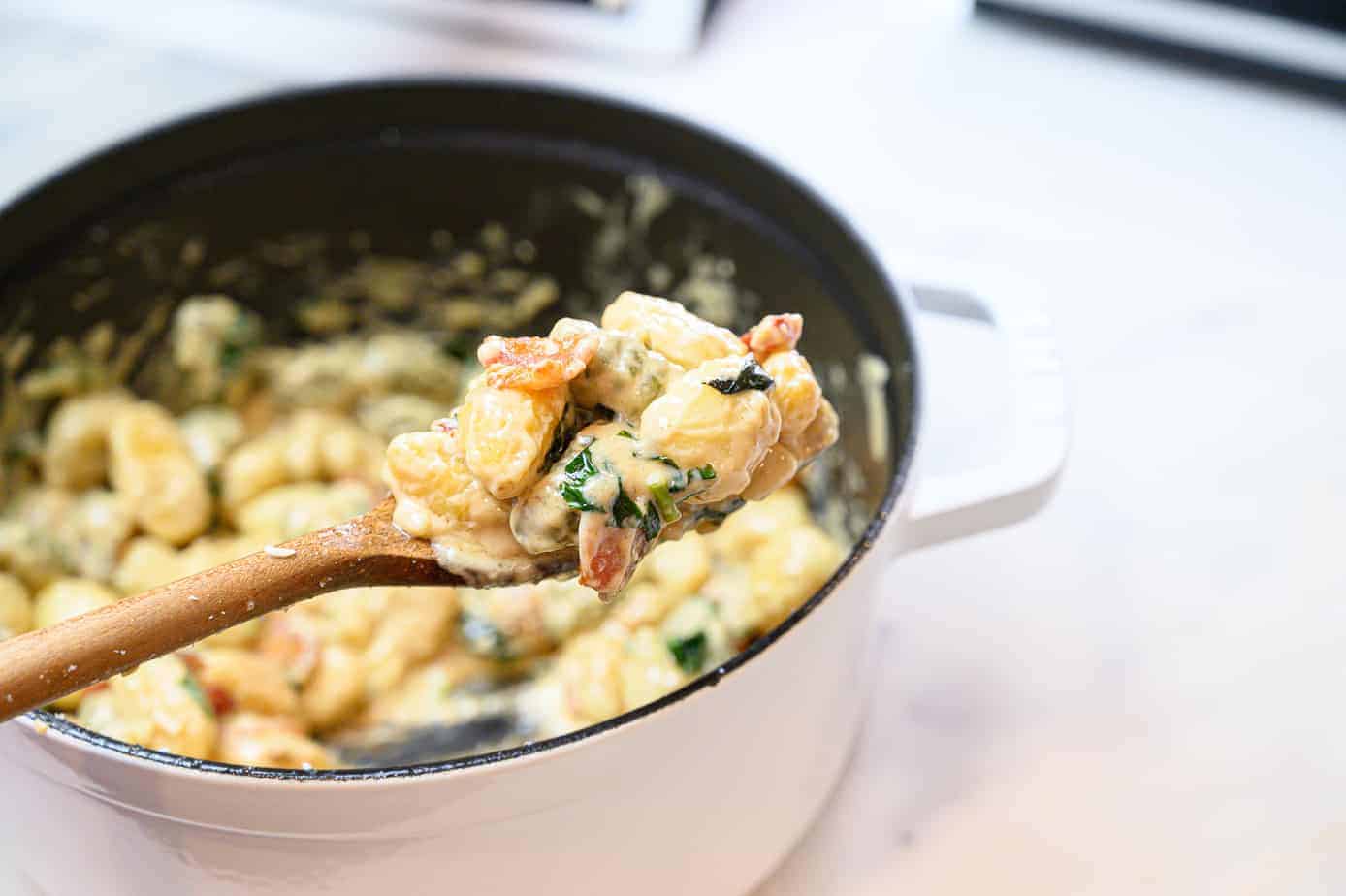 gnocchi in a dutch oven pan scooped with a wooden spoon