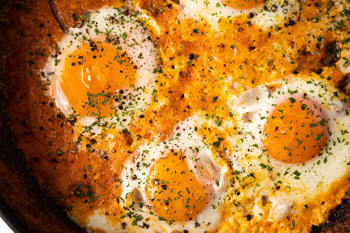 Shakshuka with three eggs and tomatoes in a pan