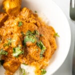indian butter chicken in a bowl topped with cilantro