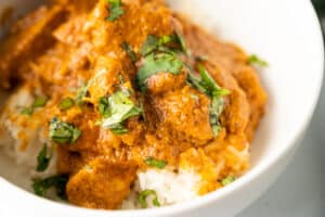 indian butter chicken in a bowl topped with cilantro