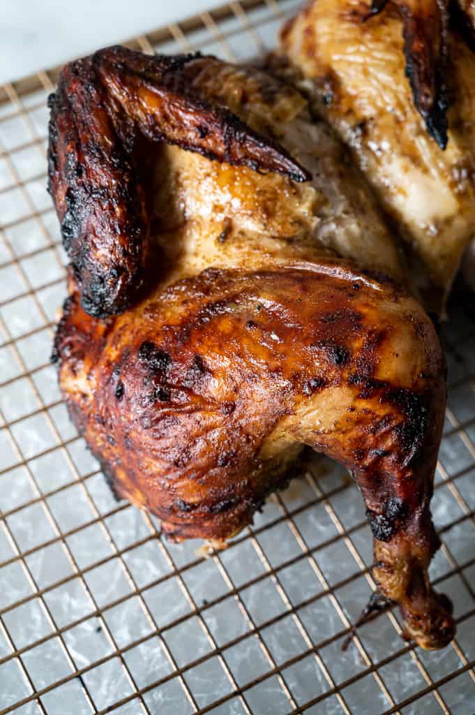 thigh and wing of a grilled, spatchcocked chicken on a wire rack