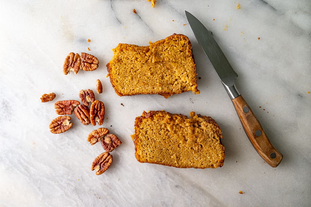 Flat lay of pecans, pumpkin bread and knife on marble board. 
