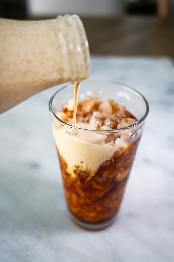 pumpkin pie coffee creamer poured into a tall glass of iced coffee