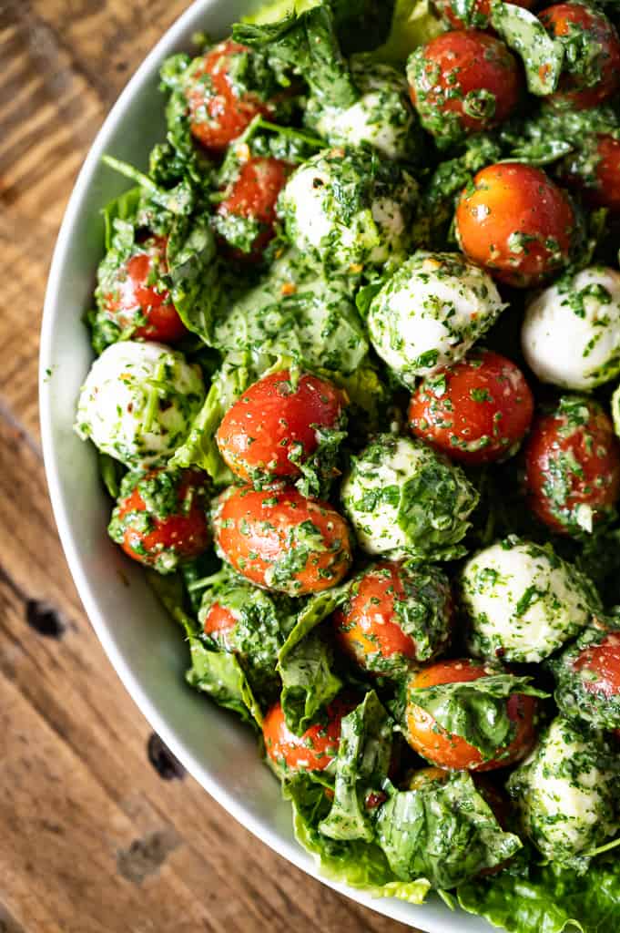 Kale Caprese Salad with wooden table in the background.