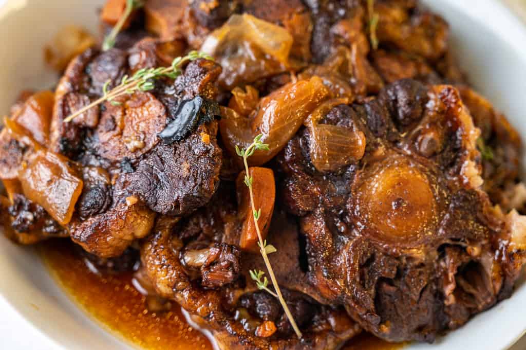 Jamaican oxtail in a bowl with gravy and thyme.