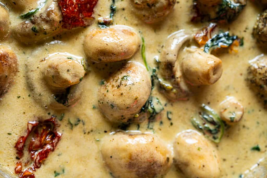 Garlic butter mushrooms in a pan with spinach and evaporated milk.