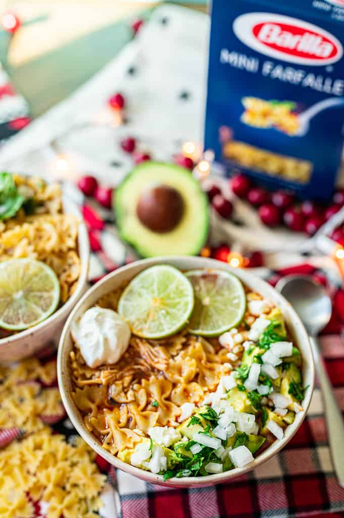 Chicken enchilada soup on table with avocado and barilla pasta
