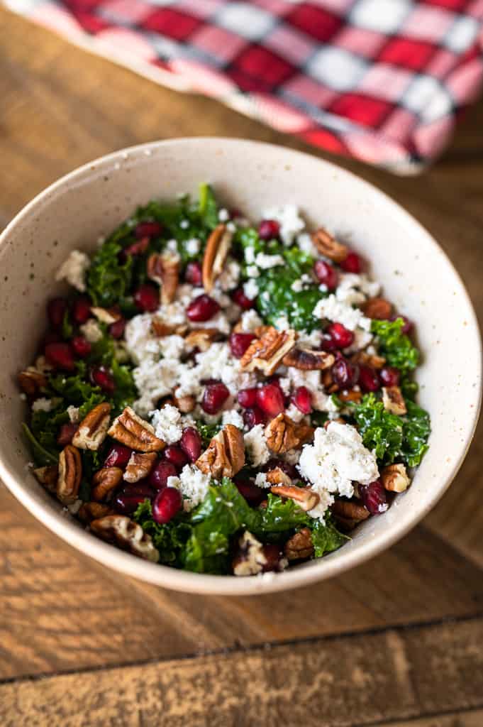 massaged kale salad in a bowl with goat cheese and pecans