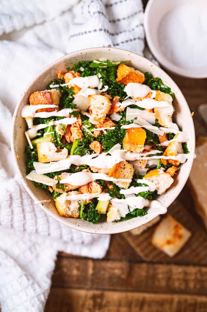salmon caesar salad with dressing drizzled over the top