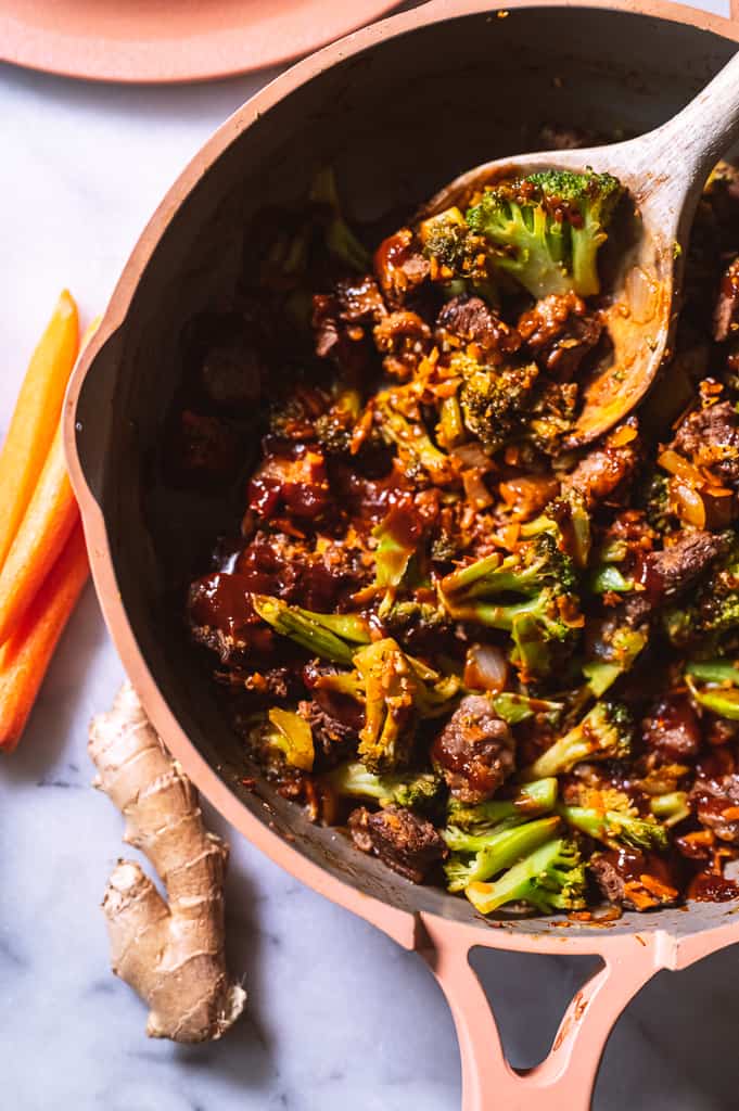 Beef and Broccoli in pan with wooden spoon.