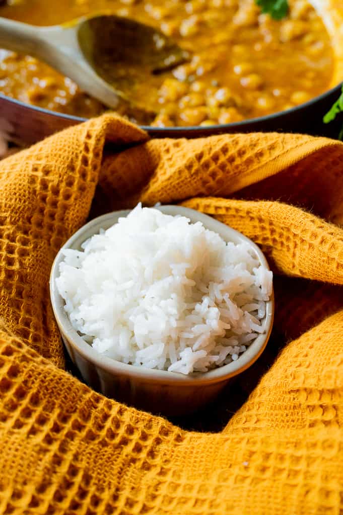 White jasmine rice in a bowl with curry behind