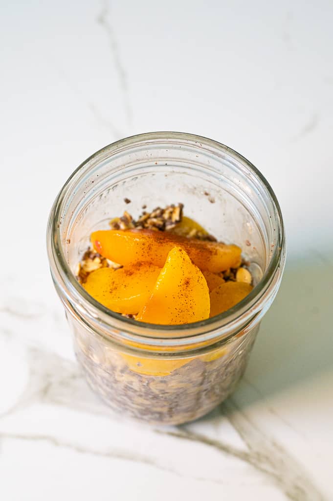 peaches and spices in a mason jar with oats for peach pie overnight oats