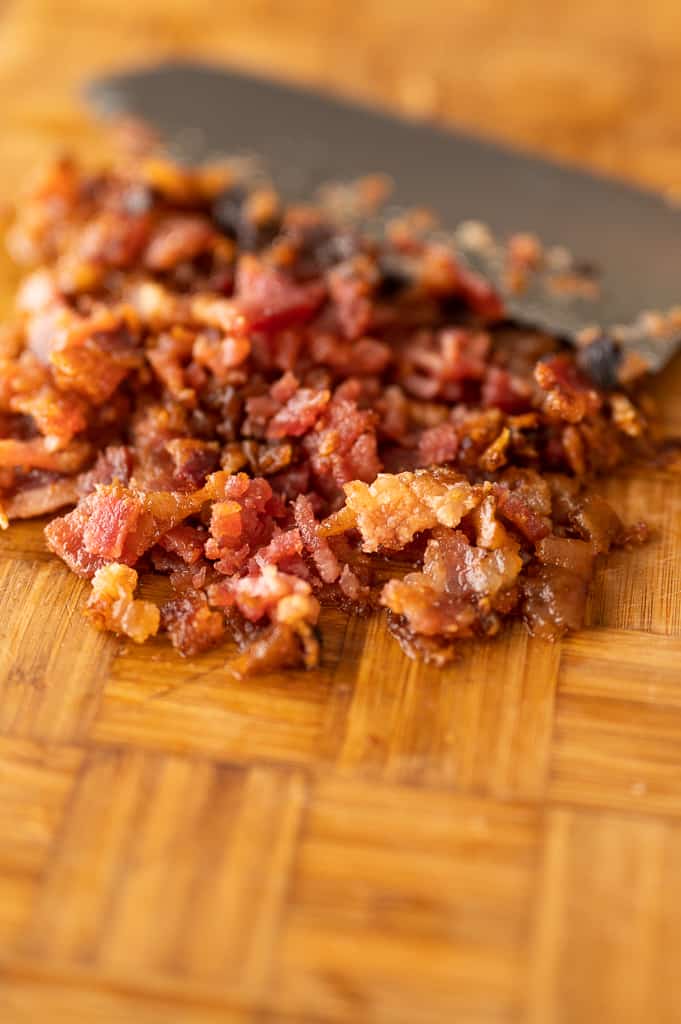 Candied bacon close up on a cutting board with a knife. 