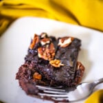 texas sheet cake on a plate with a fork and glass of milk