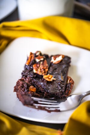 texas sheet cake on a plate with a fork and glass of milk
