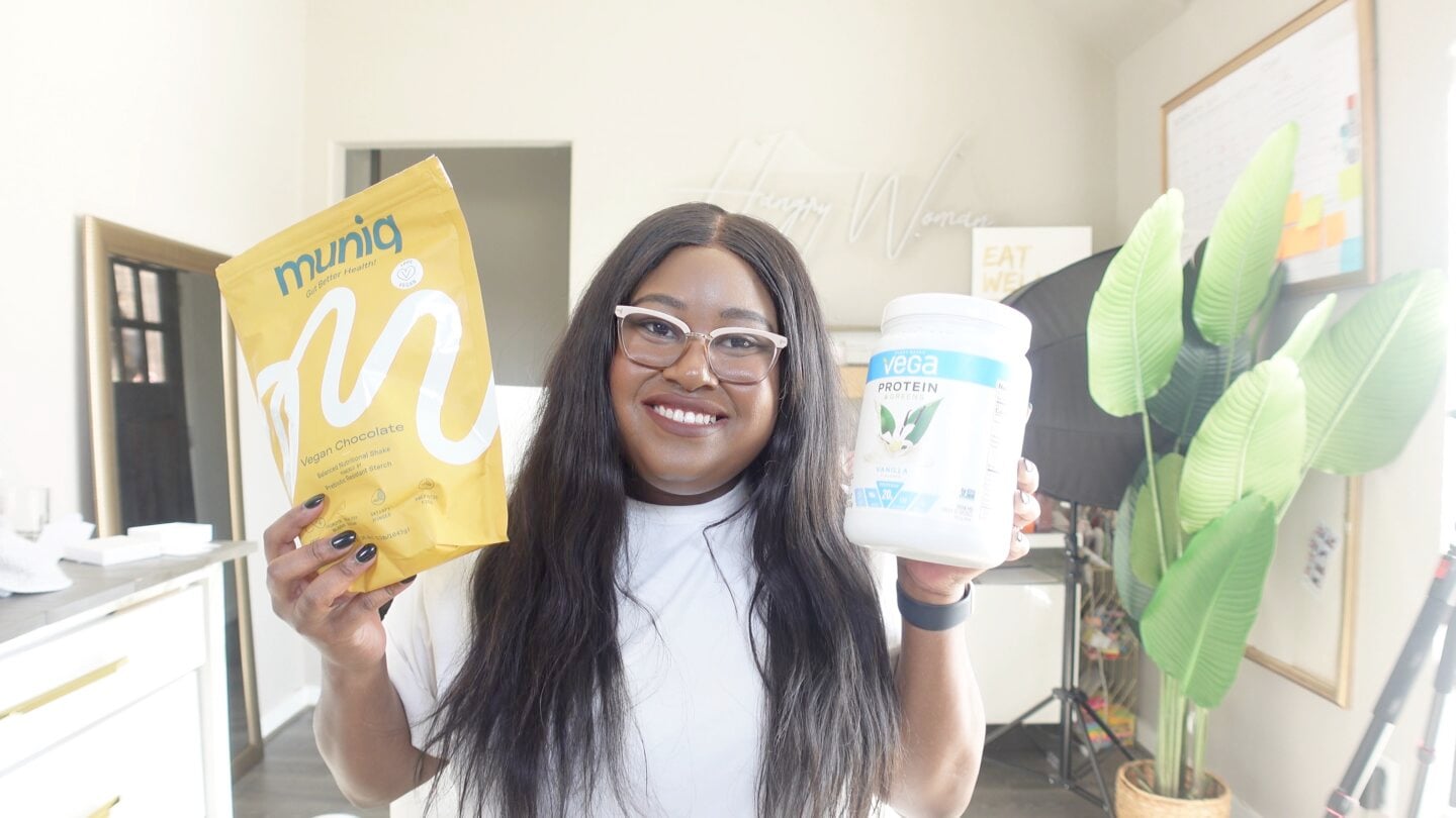 Mila holding a bag of muniq and a bottle of vega protein