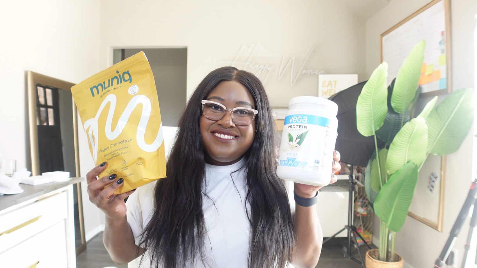 Mila holding a bag of muniq and a bottle of vega protein