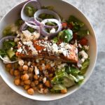 Greek-Style Salad in bowl with salmon on top