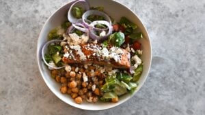 Greek-Style Salad in bowl with salmon on top