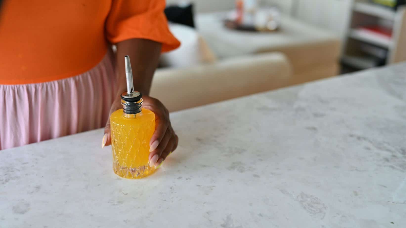 glass bitters bottle with person holding simple syrup