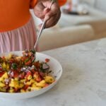 mangp pico being tossed between two bowls in a salad bowl