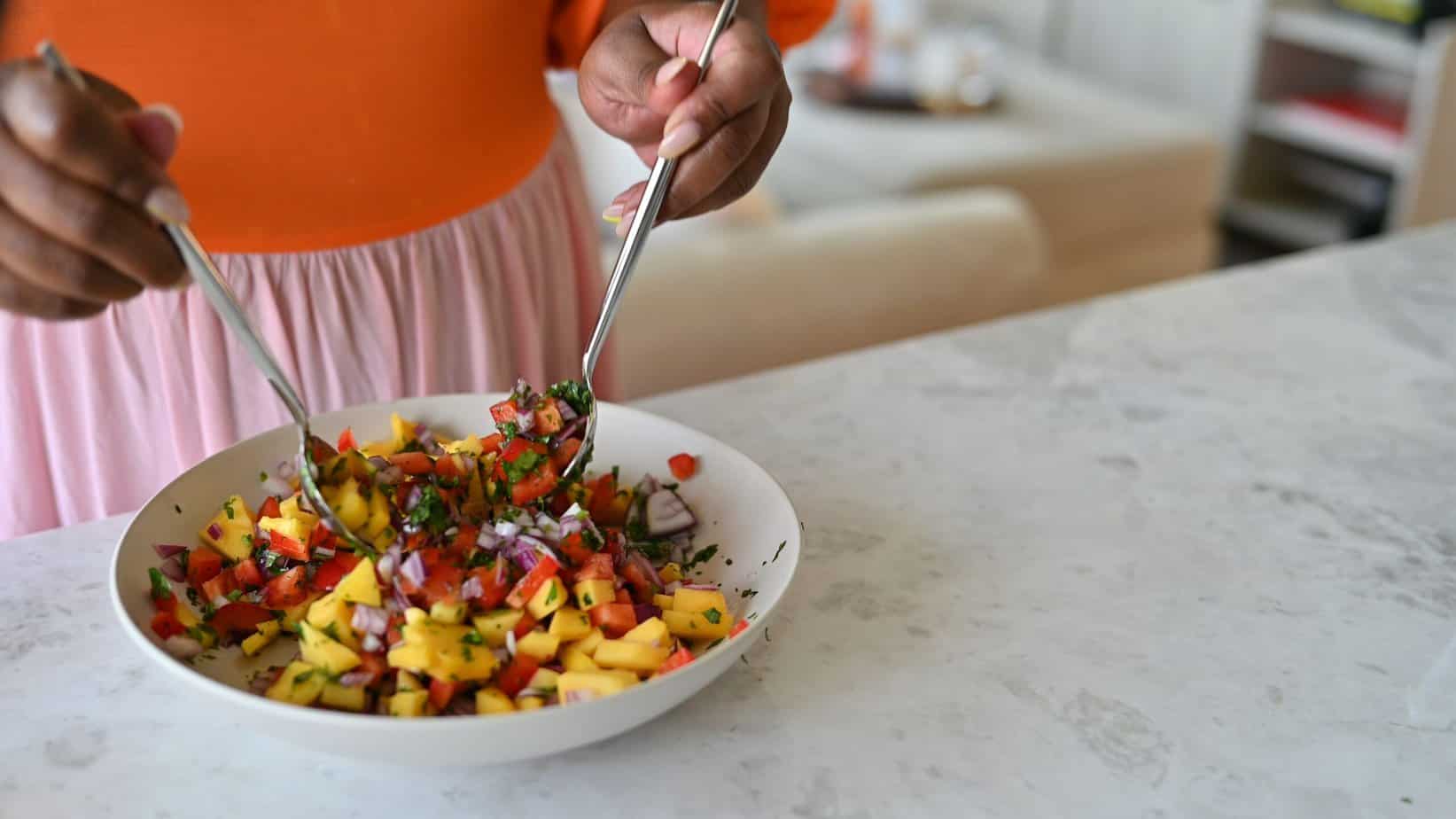 mangp pico being tossed between two bowls in a salad bowl