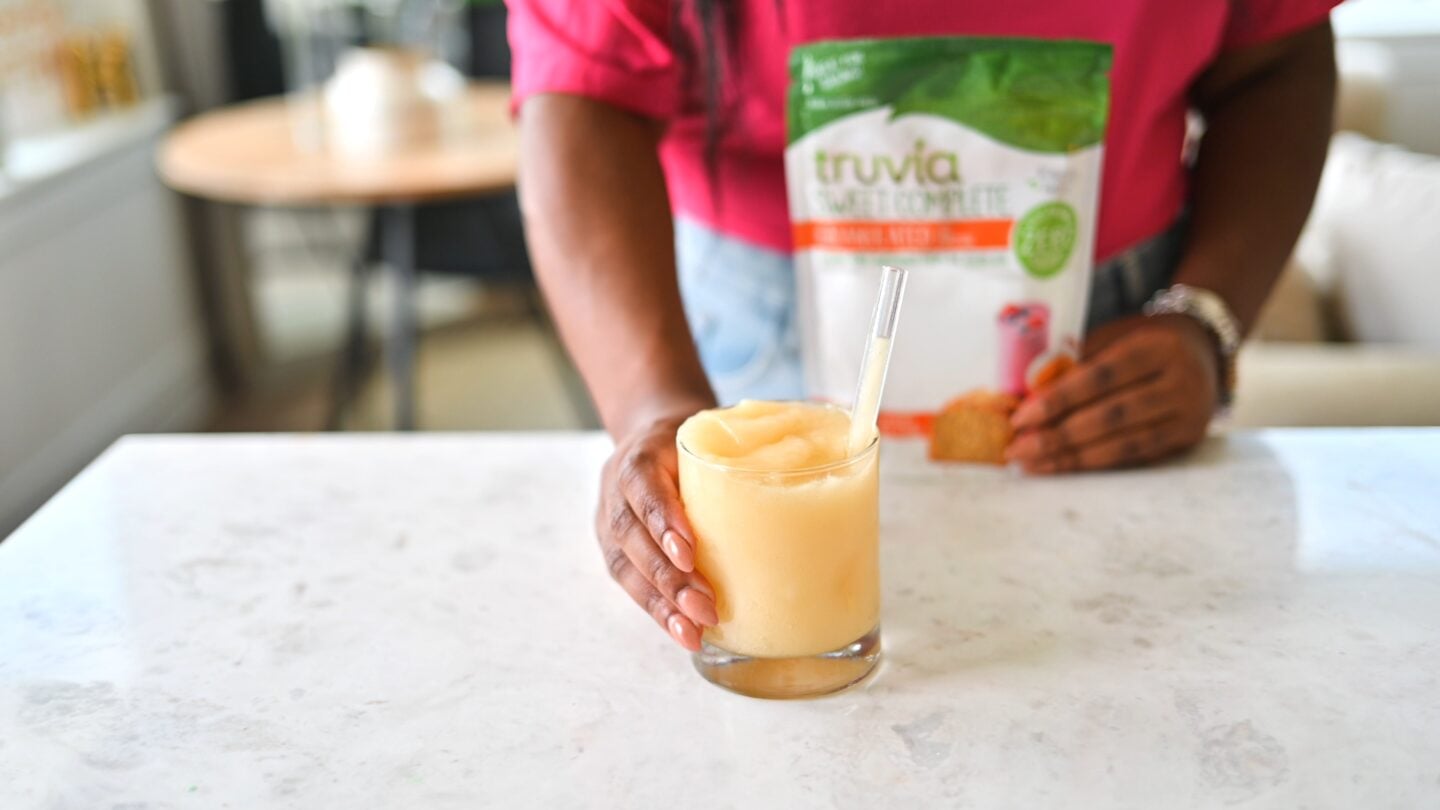 saturn cocktail in hand on counter with Truvia Sweet Complete.