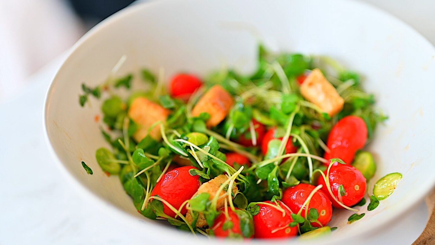 Microgreens salad in a bowl with fresh tomatoes, cucumbers and croutons