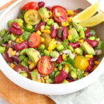 edamame salad mixed into a bowl with a wedge of lemon