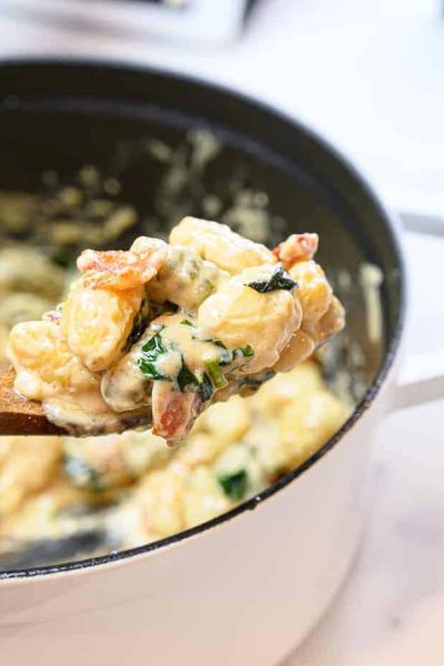 gnocchi in a dutch oven pan scooped with a wooden spoon